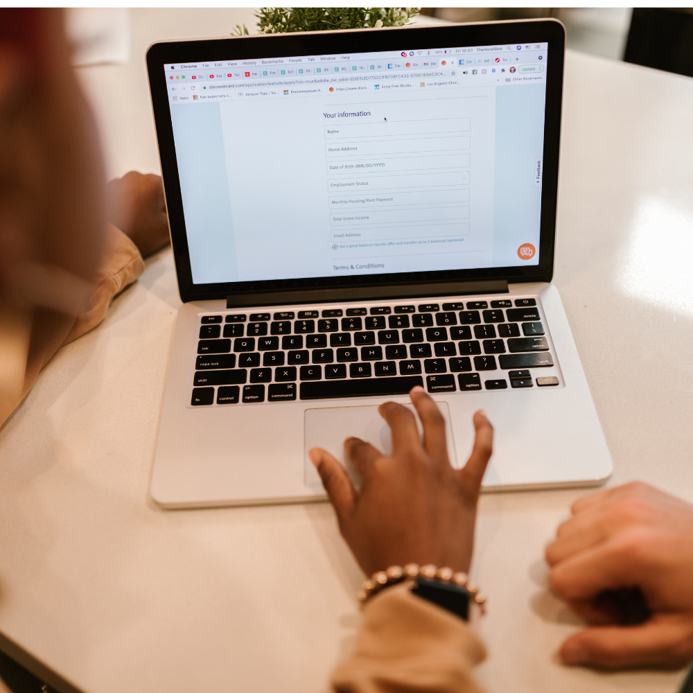 Person using a laptop to complete their onboarding form on a white surface