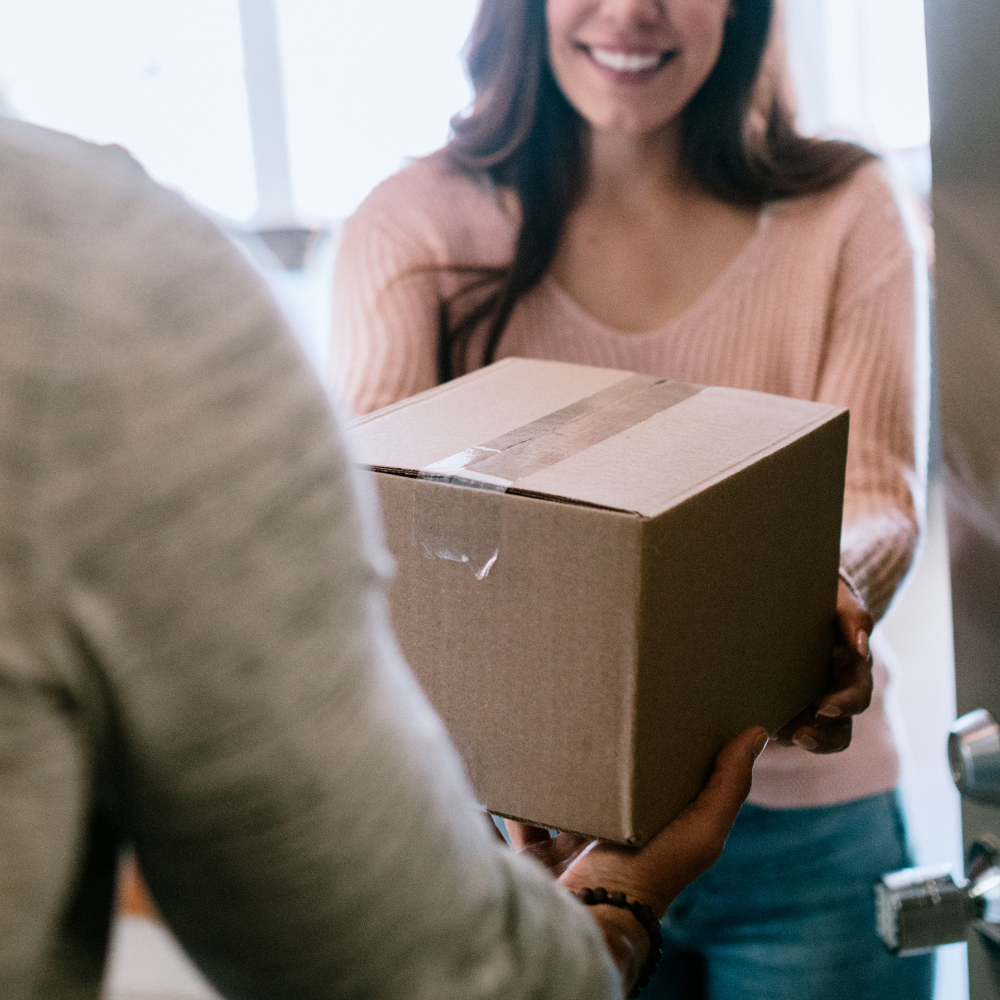 Person receiving a cardboard box from another person indoors